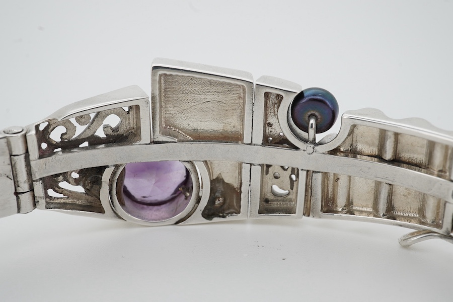 A contemporary silver and amethyst bangle, of abstract, Cubist-inspired design, to a textured band, set with a circular-cut amethyst and a cultured pearl, inner circumference approximately 20.8cm, maker's mark ZC, stampe
